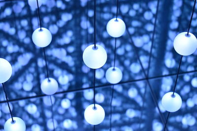 Low angle view of illuminated light bulb hanging on ceiling