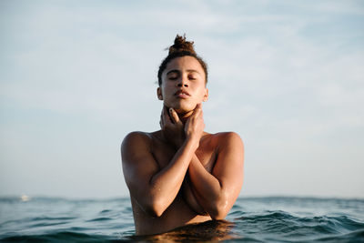 Happy young woman in sea against sky