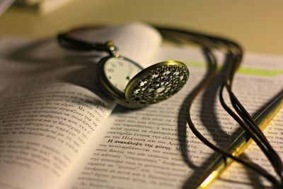 Close-up of pocket watch on open book