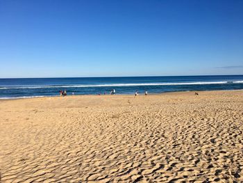 Scenic view of beach against clear blue sky