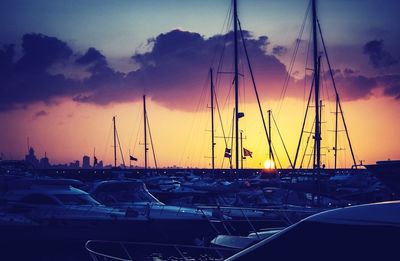 Sailboats moored at harbor during sunset