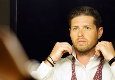 Businessman wearing tie reflecting on mirror at home