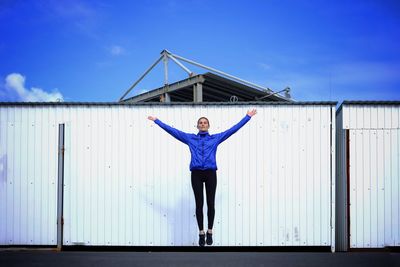 Portrait of woman jumping against blue sky