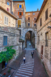 People walking on canal amidst buildings in city