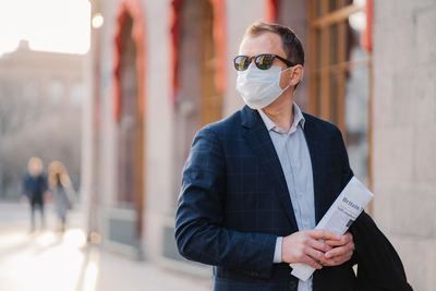 Businessman wearing mask while standing in city