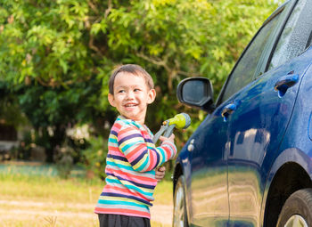 Cute boy washing car outdoors