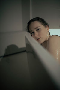 Portrait of young woman sitting on bed at home