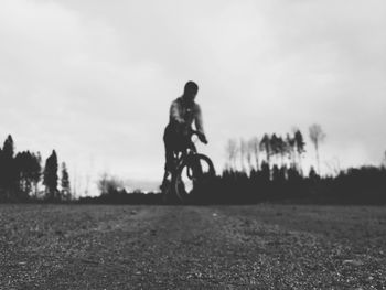 Man riding bicycle on grass against sky