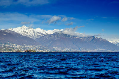 Scenic view of sea and snowcapped mountains against sky