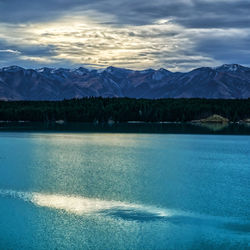 Scenic view of lake by mountains against sky