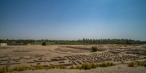 Scenic view of farm against clear blue sky