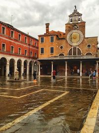 People on wet street against buildings in rainy season
