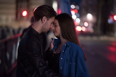Young couple kissing in city at night
