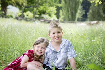 Young boy and girl sitting in green grass looking at the camera