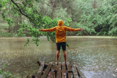 Full length of man standing by lake in forest