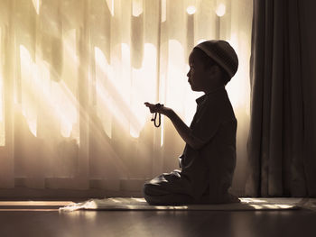 Side view of man sitting against wall at home