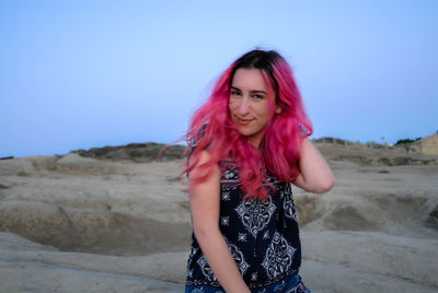 Portrait of smiling young woman standing against clear sky