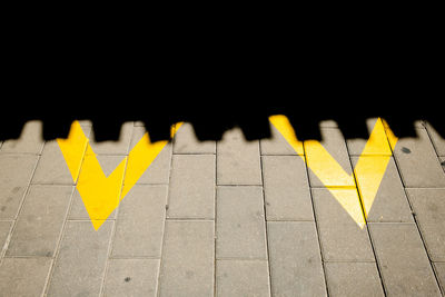 High angle view of yellow arrow symbol on footpath