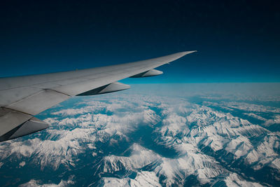 Aerial view of snowcapped mountain against blue sky