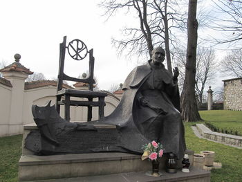 Statue of people at cemetery against sky