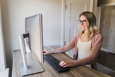 Portrait of smiling woman sitting on table at home