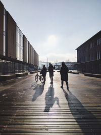 Rear view of people walking on road against sky