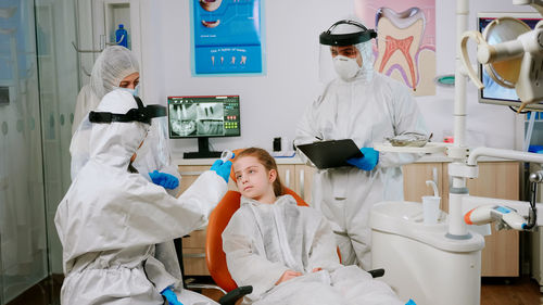 Dentist checking temperature of girl at clinic