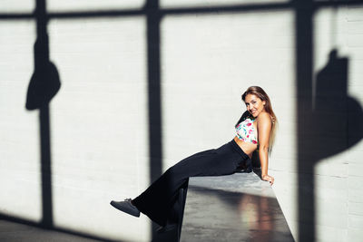 Portrait of woman sitting against wall