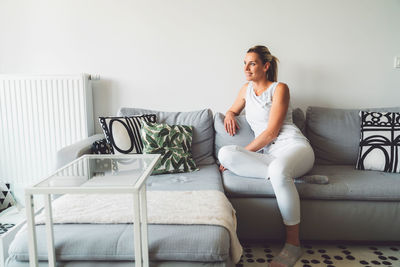 Young woman sitting on sofa at home