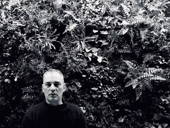 Portrait of young man standing against trees