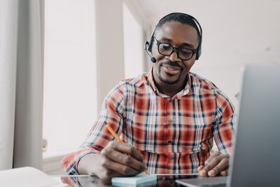 Portrait of young man using mobile phone while standing at home