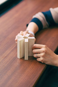 Cropped image of woman hand holding wooden blocks at table