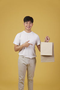 Portrait of smiling boy standing against yellow background