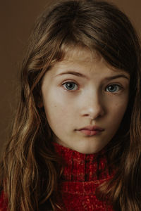 Close-up portrait of serious girl against brown background