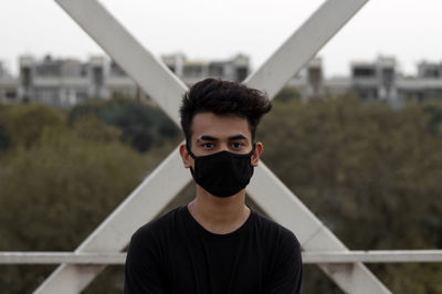 Portrait of young man standing against railing