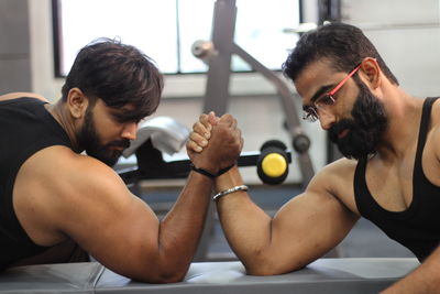 Male friends arm wrestling at gym