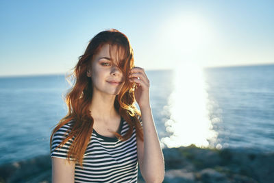 Portrait of smiling young woman against sea