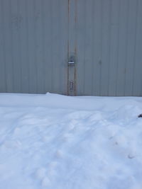 Snow covered metal door of building