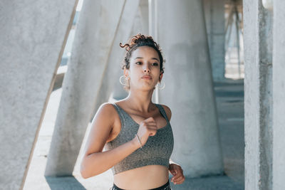 Portrait of young woman standing against wall