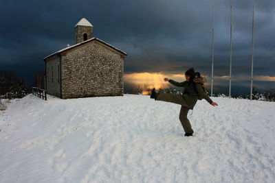 Full length of person on snow covered land against building