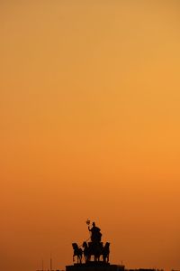 Silhouette statue against orange sky