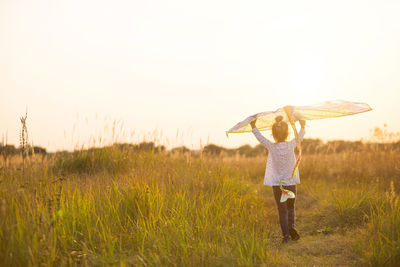 Girl holding kite standing on field