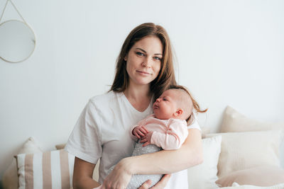 Portrait of a young attractive red-haired mother holding and hugging her newborn daughter.