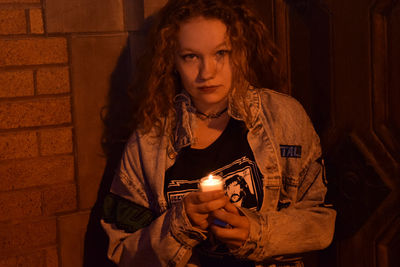 Portrait of woman holding tea light candle at night