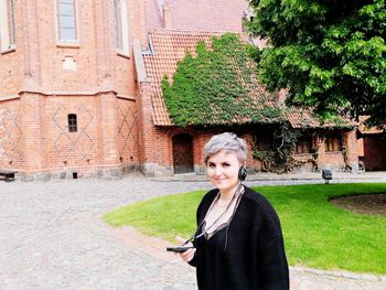 Young woman standing by tree against building