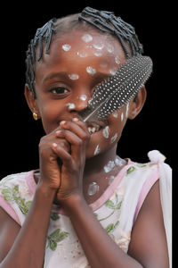 Portrait of young woman drinking water against black background