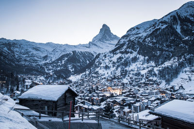 Snow covered houses and mountains against sky