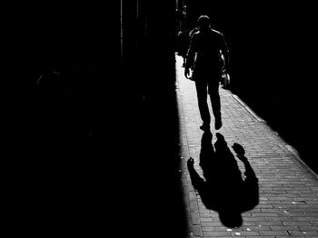 Rear view of silhouette man walking on street