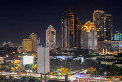 Illuminated buildings in city against sky at night