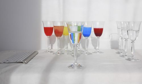 Close-up of wineglasses with keyboard on table against wall